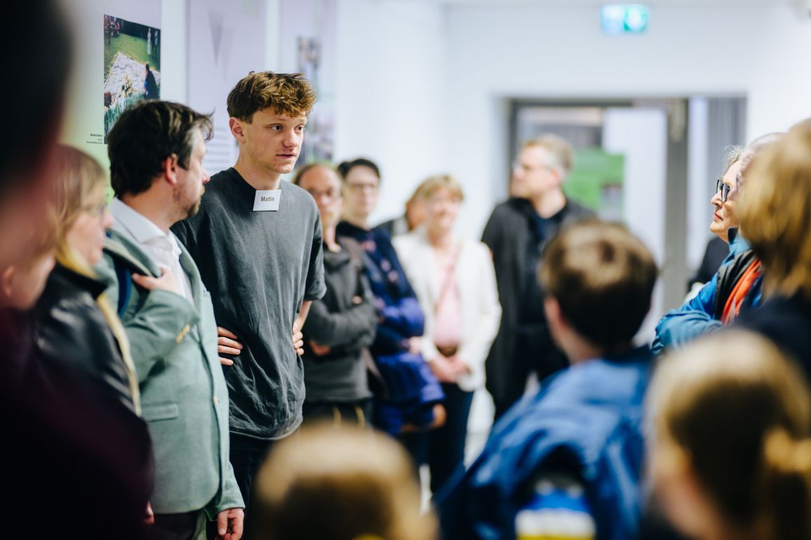 Mattis Schulte erklärt seine Ausstellung "25 Jahre Verein Gedenktag 2. April | Gedenken und Begegnen – Auseinandersetzen und Verstehen."